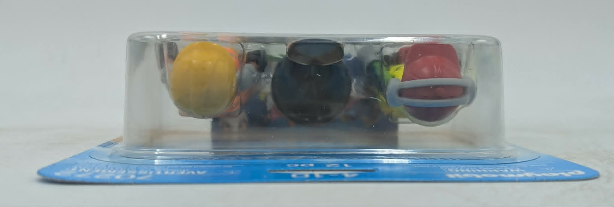 Drei Spielzeugfiguren in einer Plastikverpackung: gelb, schwarz und rot.