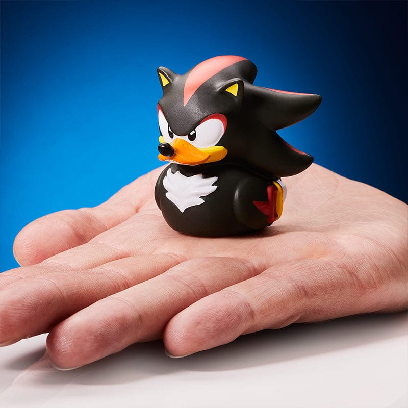 Ein Shadow the Hedgehog Quietscheentchen sitzt auf einer Hand vor blauem Hintergrund.