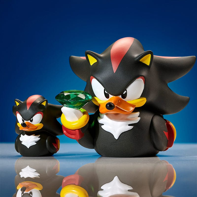 Zwei Shadow the Hedgehog Gummienten, eine hält einen grünen Edelsteinring, vor blauem Hintergrund.