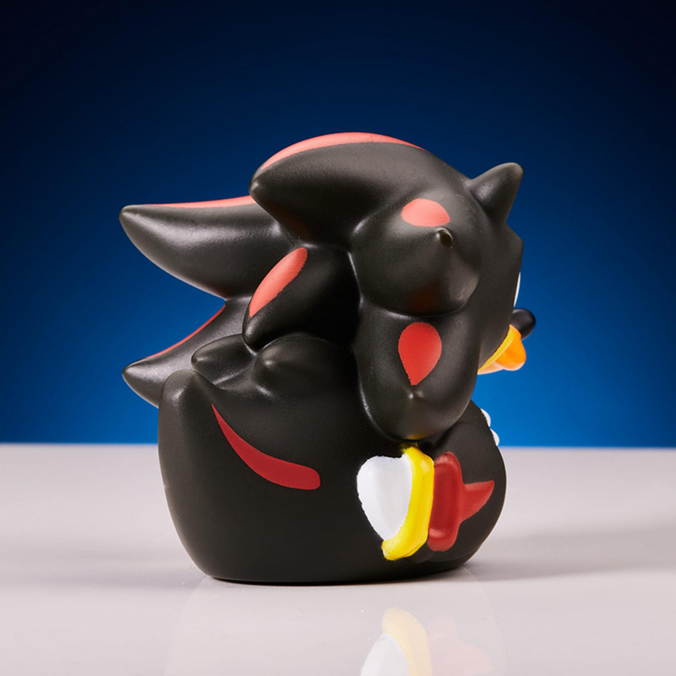 Schwarze Figur mit roten Akzenten, die wie eine Ente geformt ist.