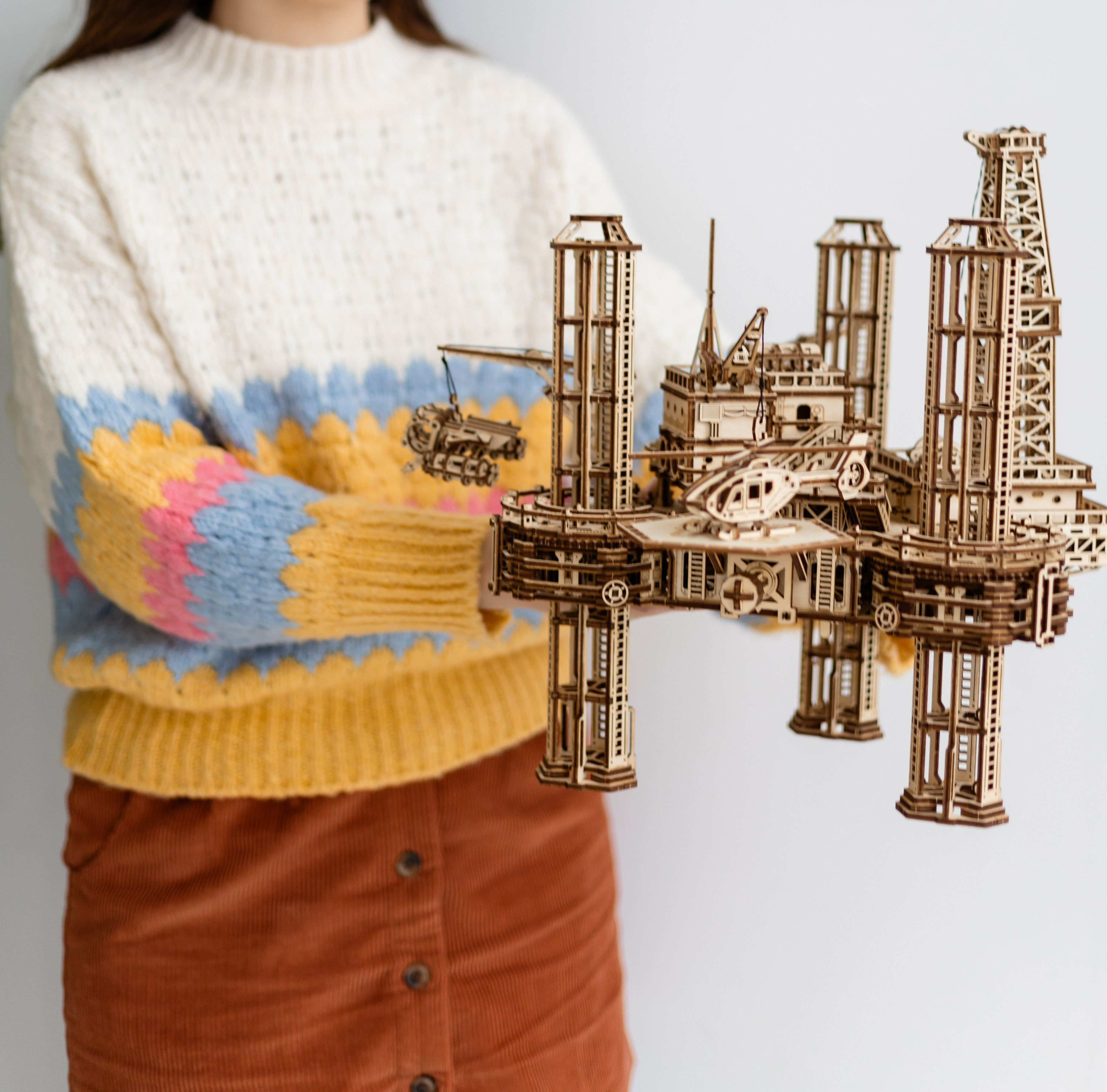 Ein Holzmodell einer Ölplattform mit Helikopter und Kran, gehalten von einer Person.