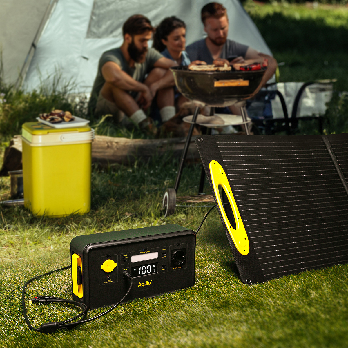 Drei Personen grillen vor einem Zelt, daneben eine Powerstation und ein Solarpanel.