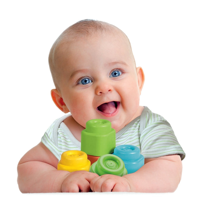 Ein Baby mit blauen Augen lacht und hält bunte Bausteine.