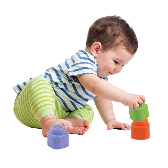 Baby im gestreiften Hemd und grüner Hose spielt mit bunten Bausteinen.