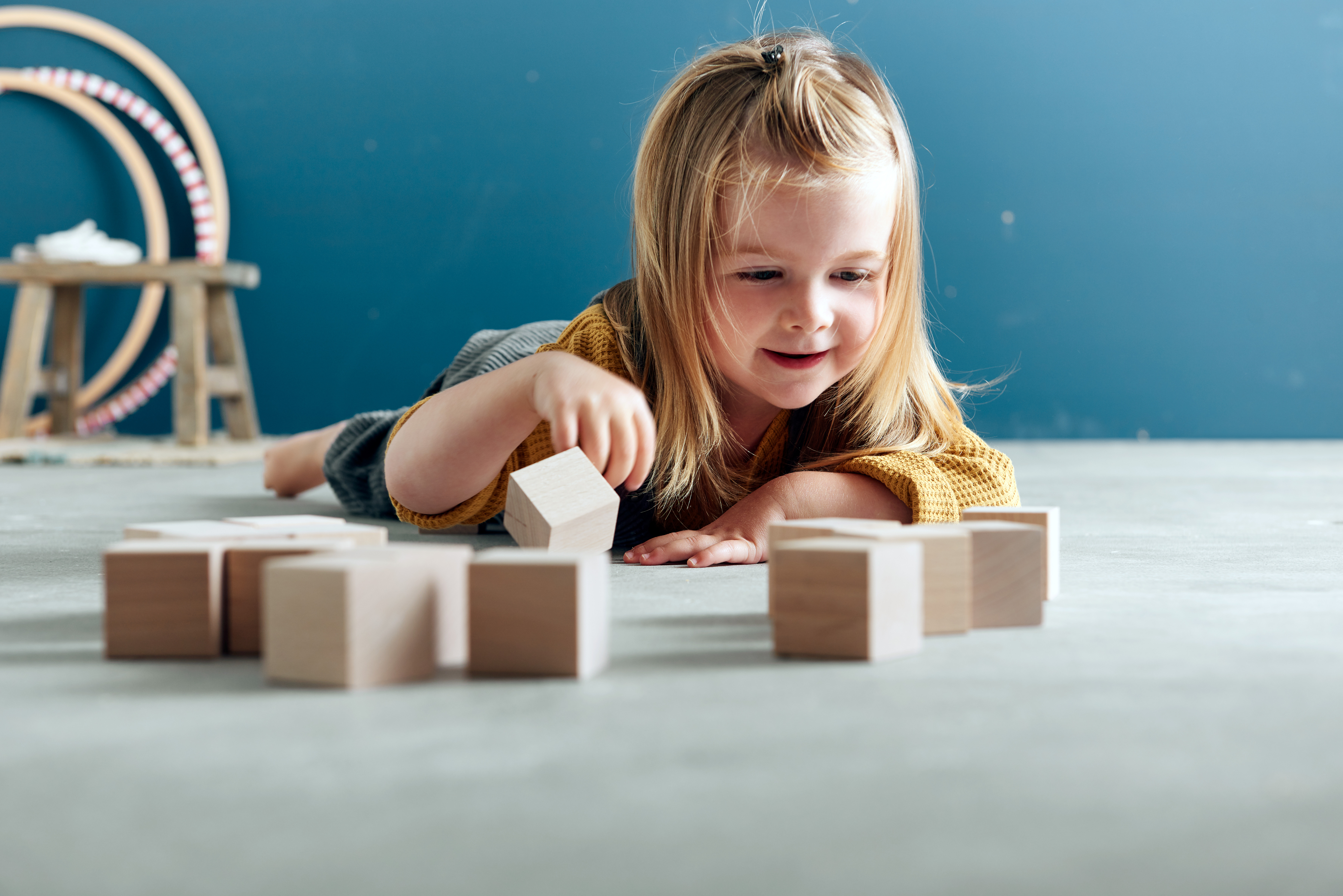 Una bambina gioca con blocchi di legno sul pavimento.