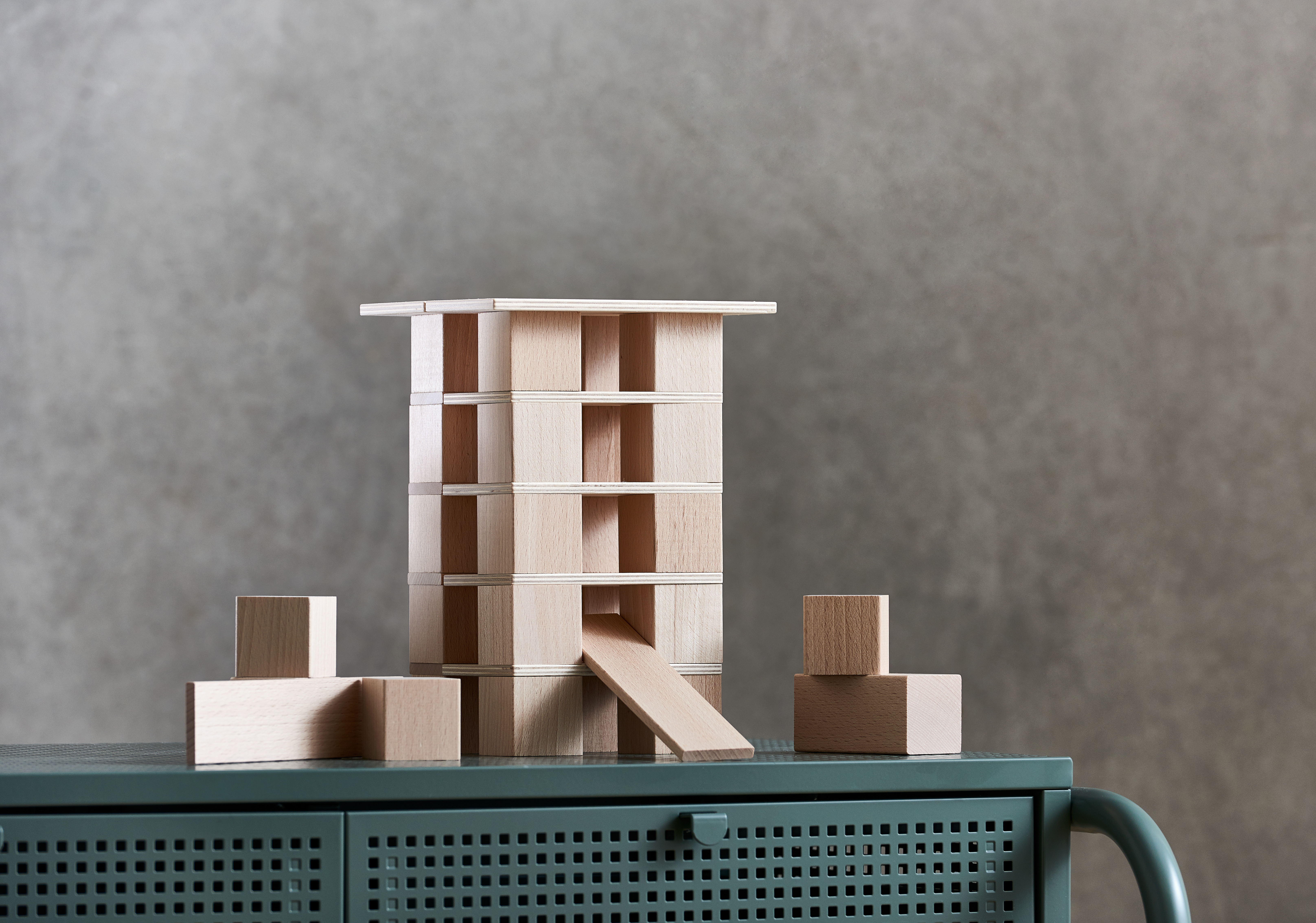 Una torre di legno fatta di blocchi e una rampa su un armadio verde.