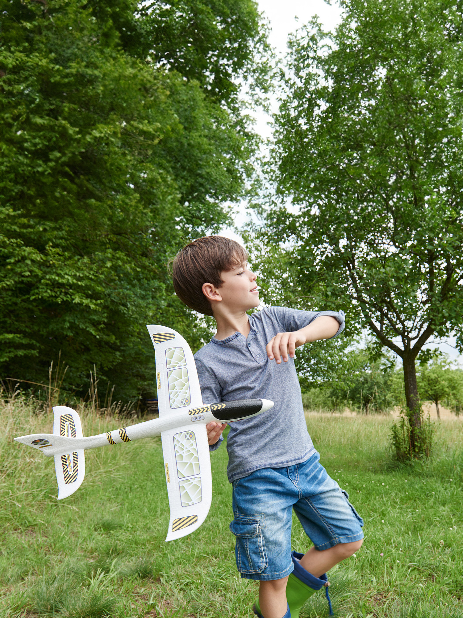 Ein Junge hält ein weies Spielzeugflugzeug im Freien.