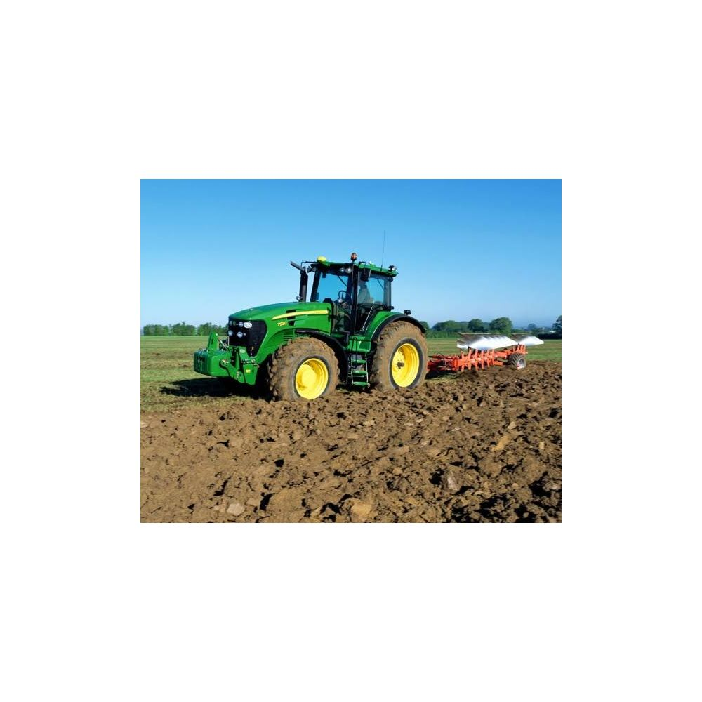 Un trattore verde con cerchi gialli ara un campo sotto un cielo blu.