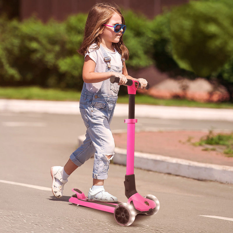 Ein Mädchen fährt einen pinken Roller mit leuchtenden Rädern auf einer Stra ße.
