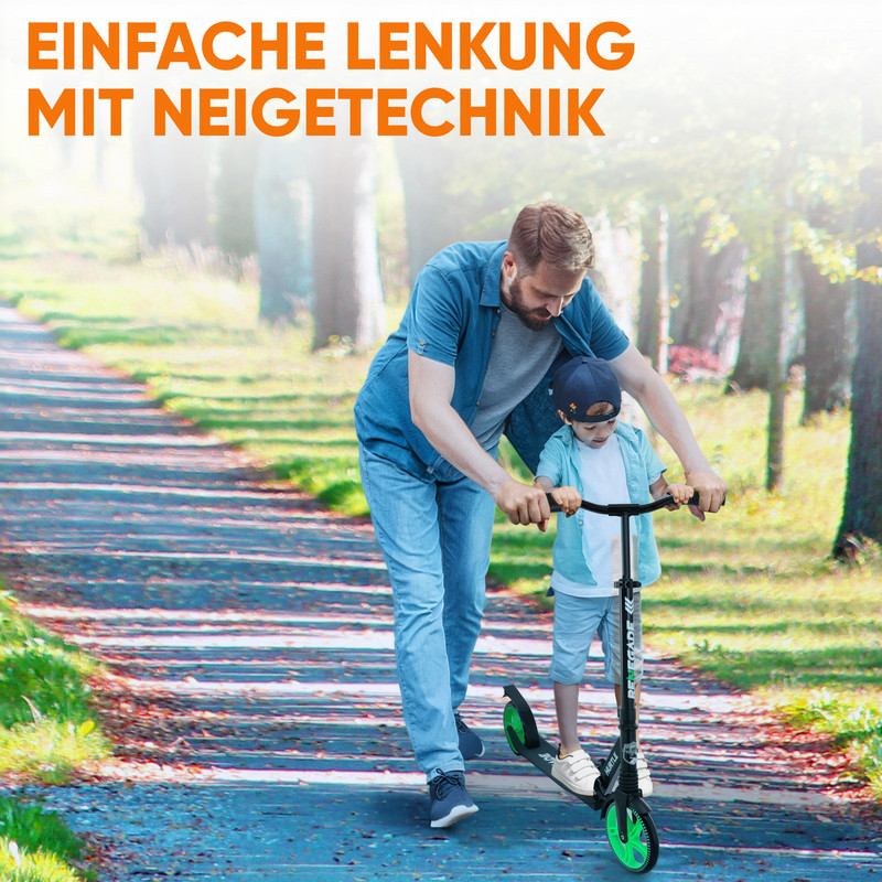 Ein Mann hilft einem Kind auf einem Roller auf einem Weg im Freien.