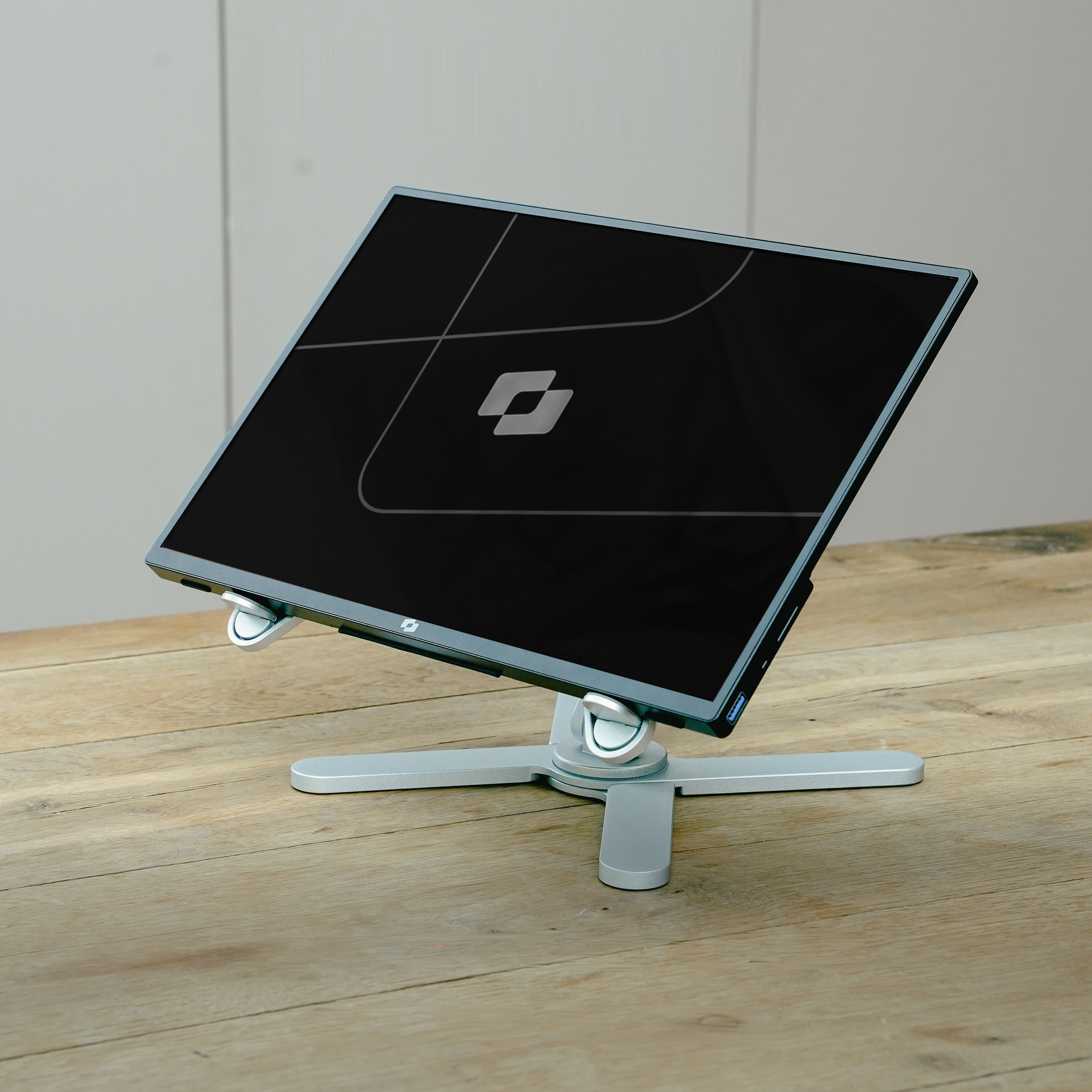 A black monitor on a silver stand resting on a wooden table.