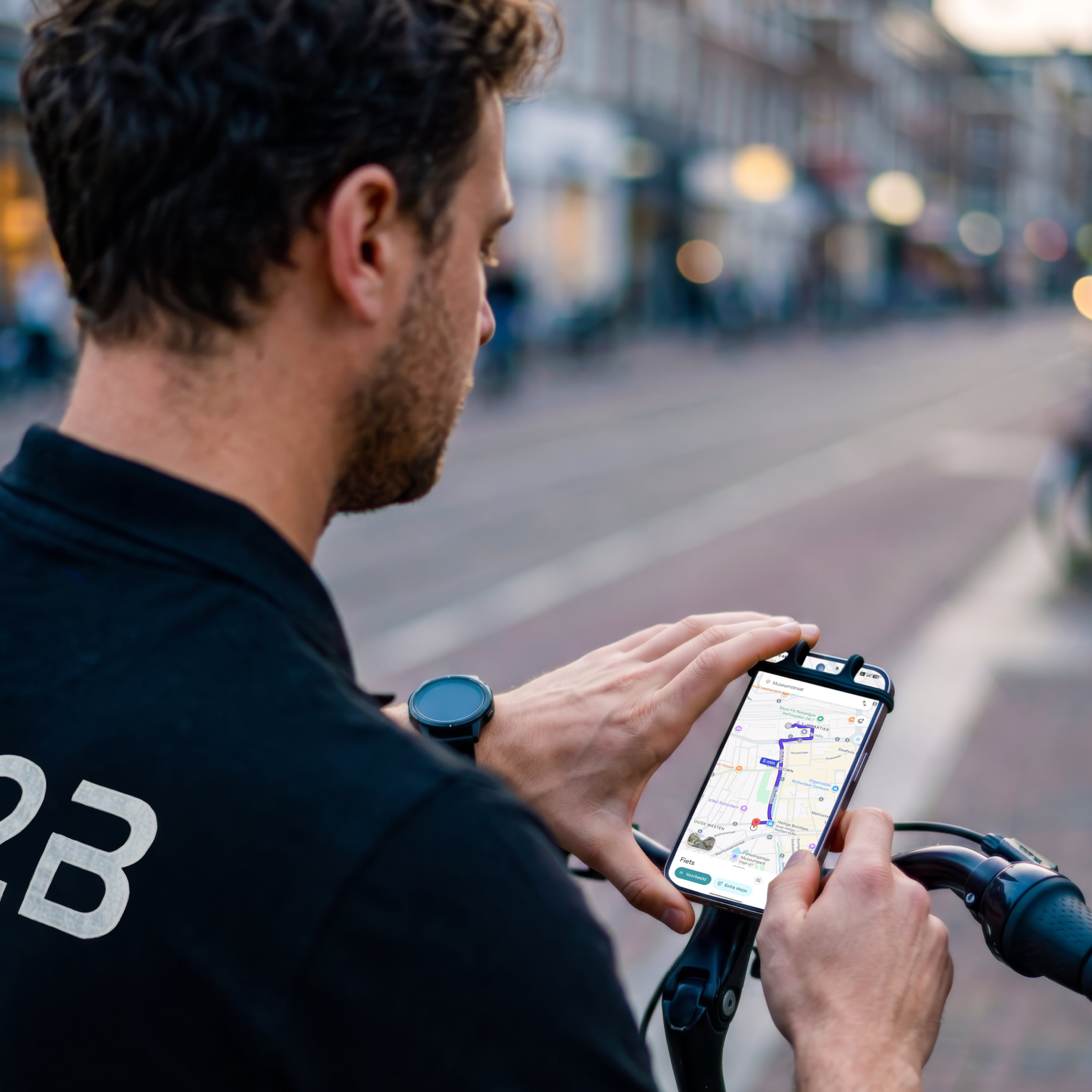 Mann mit Fahrrad navigiert mit Handy-App, Stadtansicht im Hintergrund.