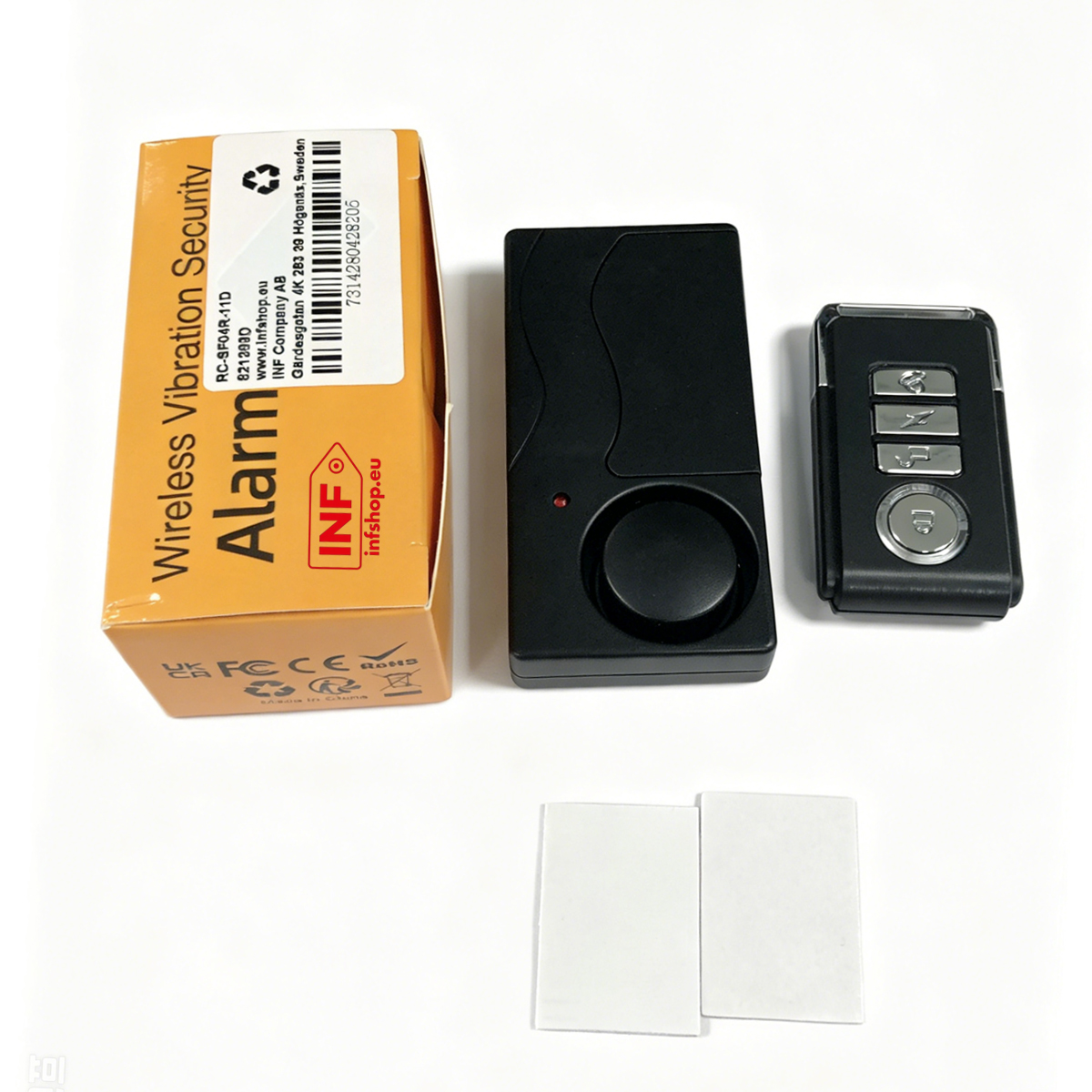 A box with alarm graphics, a black alarm detector, and a key fob.