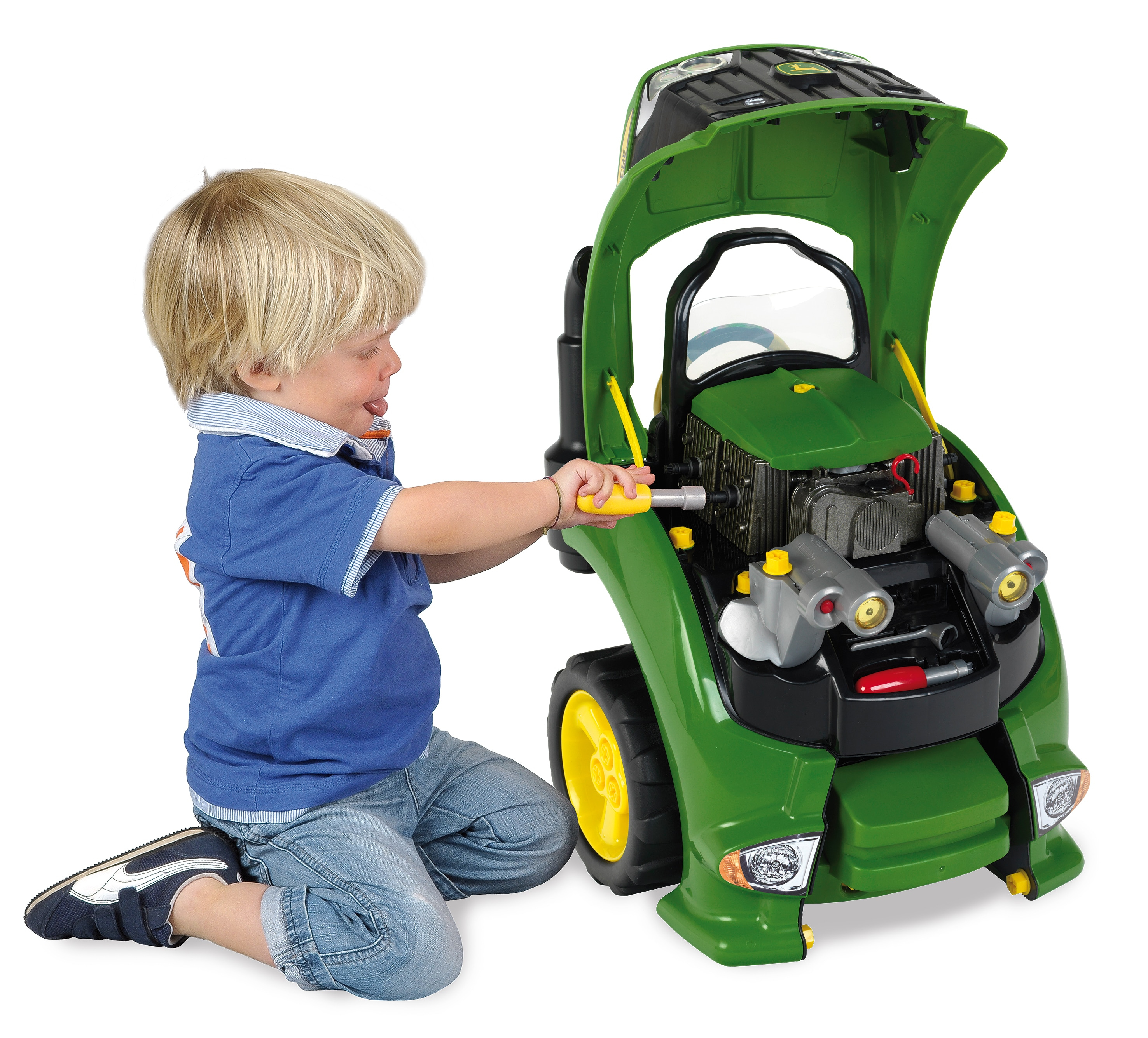 Un niño rubio trabaja en un tractor de juguete verde con una herramienta.