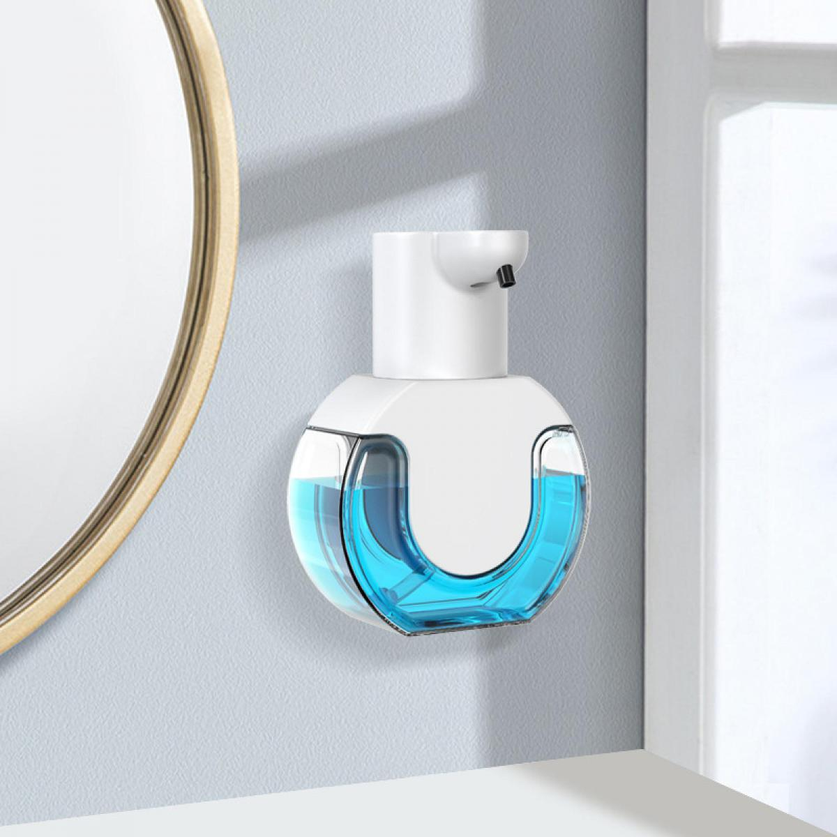 Ein weißer automatischer Seifenspender mit blauem Inhalt an einer Wand neben einem Spiegel.