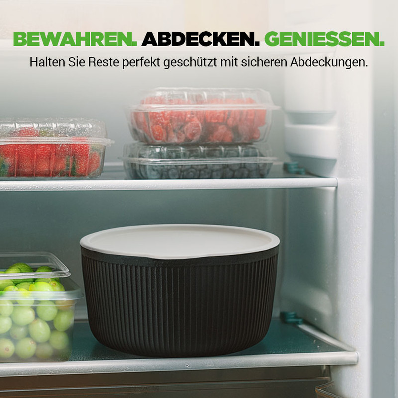 Ein Kühlschrank mit Beeren und Trauben in Plastikbehältern und einer schwarzen Schüssel.