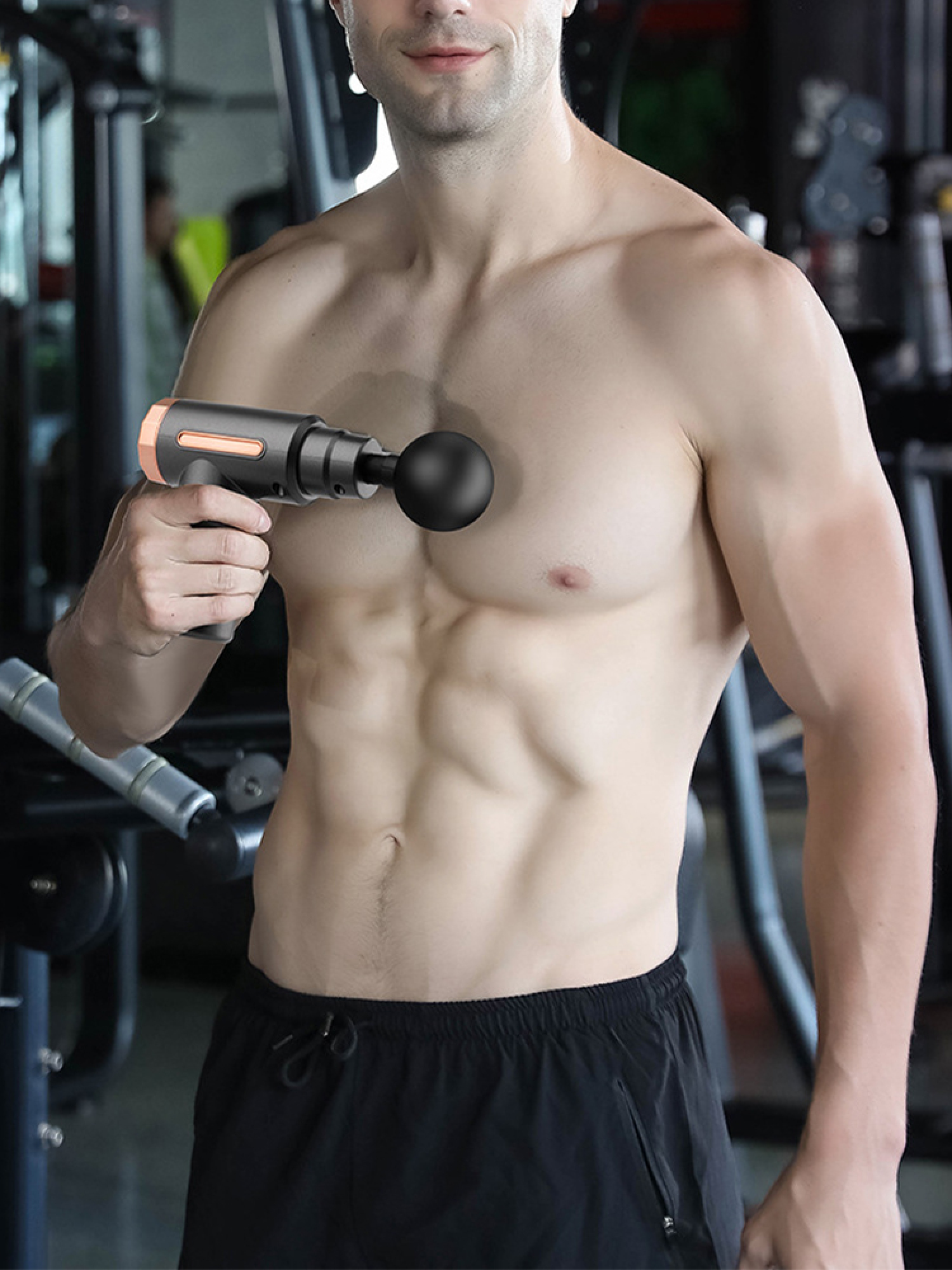 Ein Mann im Fitnessstudio hält eine Massagepistole, die er auf seiner Brust anwendet.