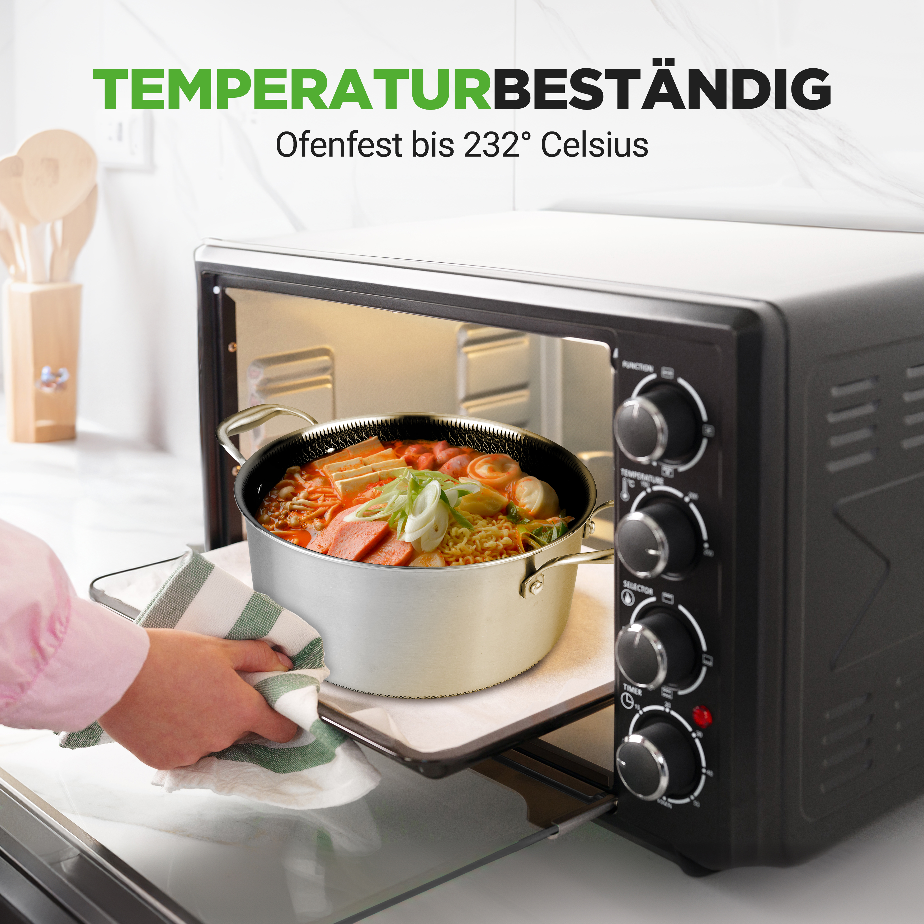 Ein Topf mit Essen wird in einen Ofen geschoben. Der Topf enthält Nudeln, Würstchen und Gemüse.