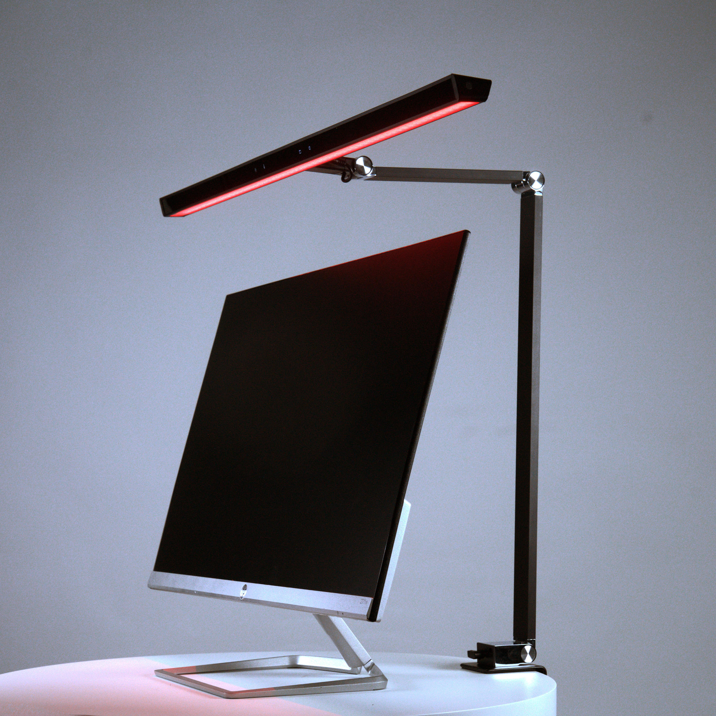 Ein moderner Schreibtisch mit einem Monitor und einer roten LED-Lampe.