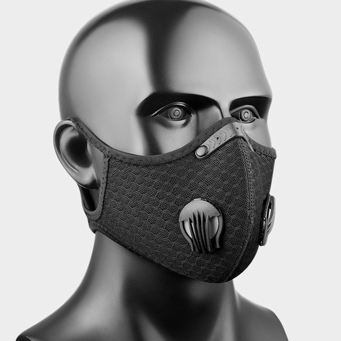 Schwarze Atemschutzmaske mit Ausatemventilen, auf einer dunklen Büste.