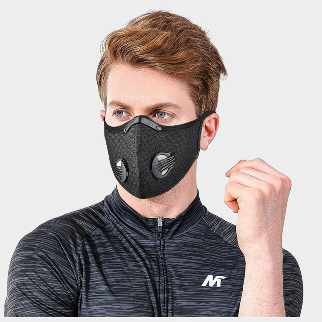 Mann mit schwarzer Gesichtsmaske und Atemventilen, trägt ein Sporthemd.