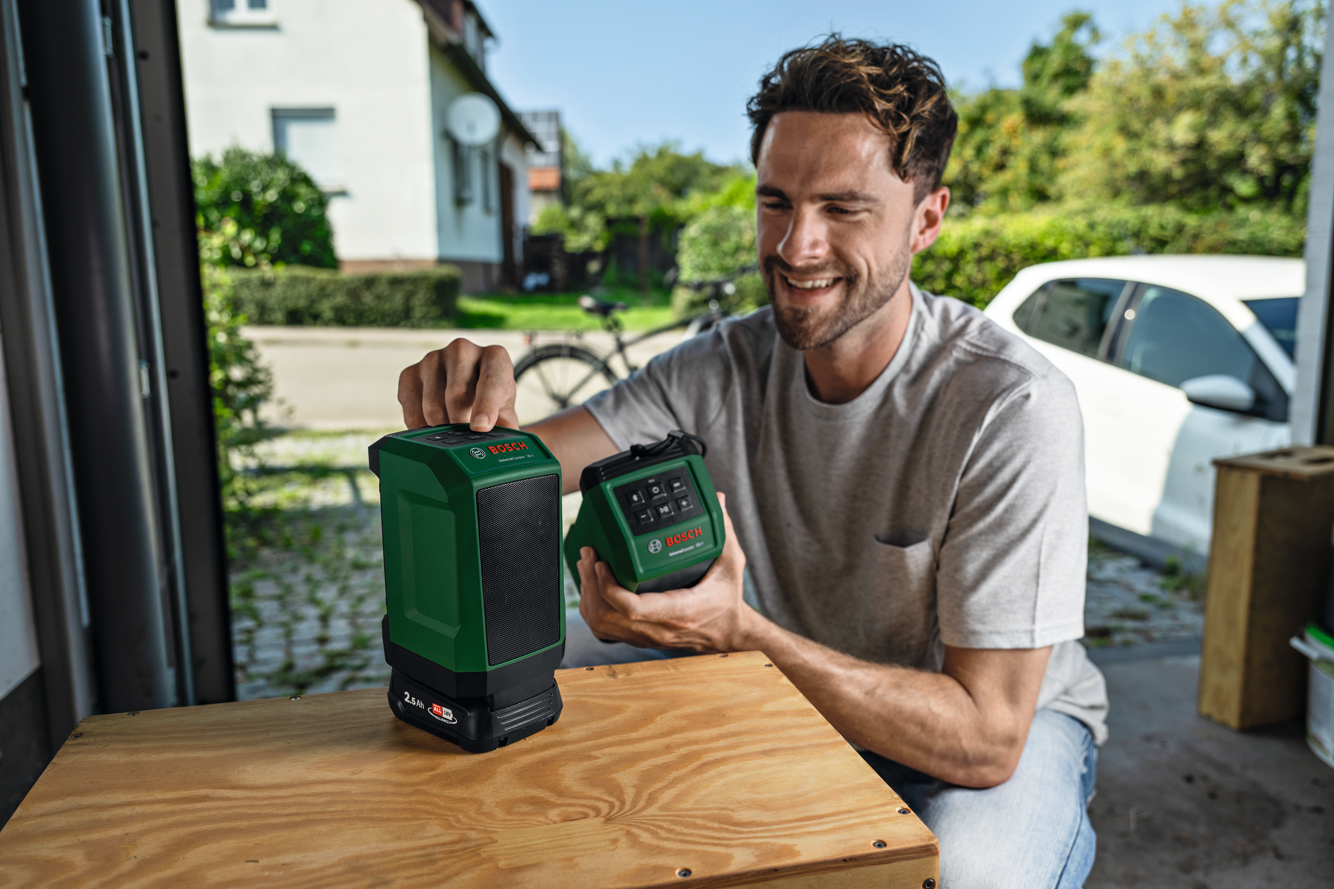 Ein Mann hält zwei grüne Bosch-Geräte in einem Freien.