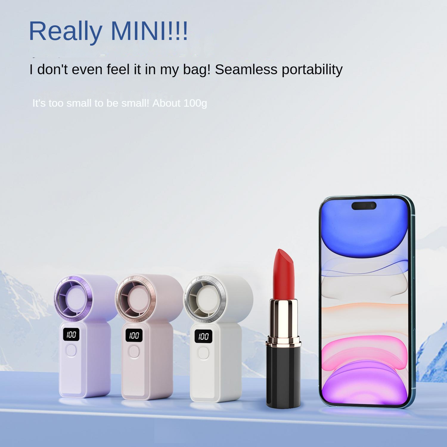 Drei kleine Lüfter, Lippenstift und ein Smartphone auf einem blauen Tisch.