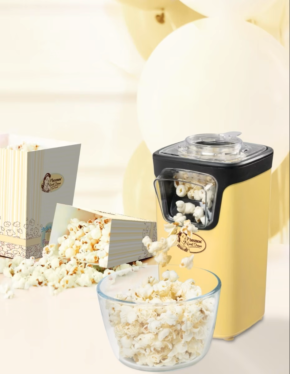 Una macchina per popcorn gialla fa popcorn in una ciotola di vetro.
