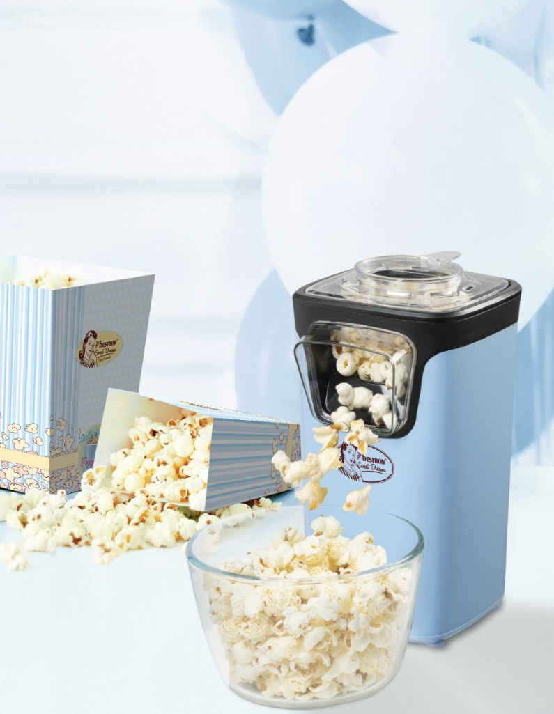 Una macchina per popcorn azzurra eroga popcorn in una ciotola di vetro. I popcorn fuoriescono da una scatola a righe.