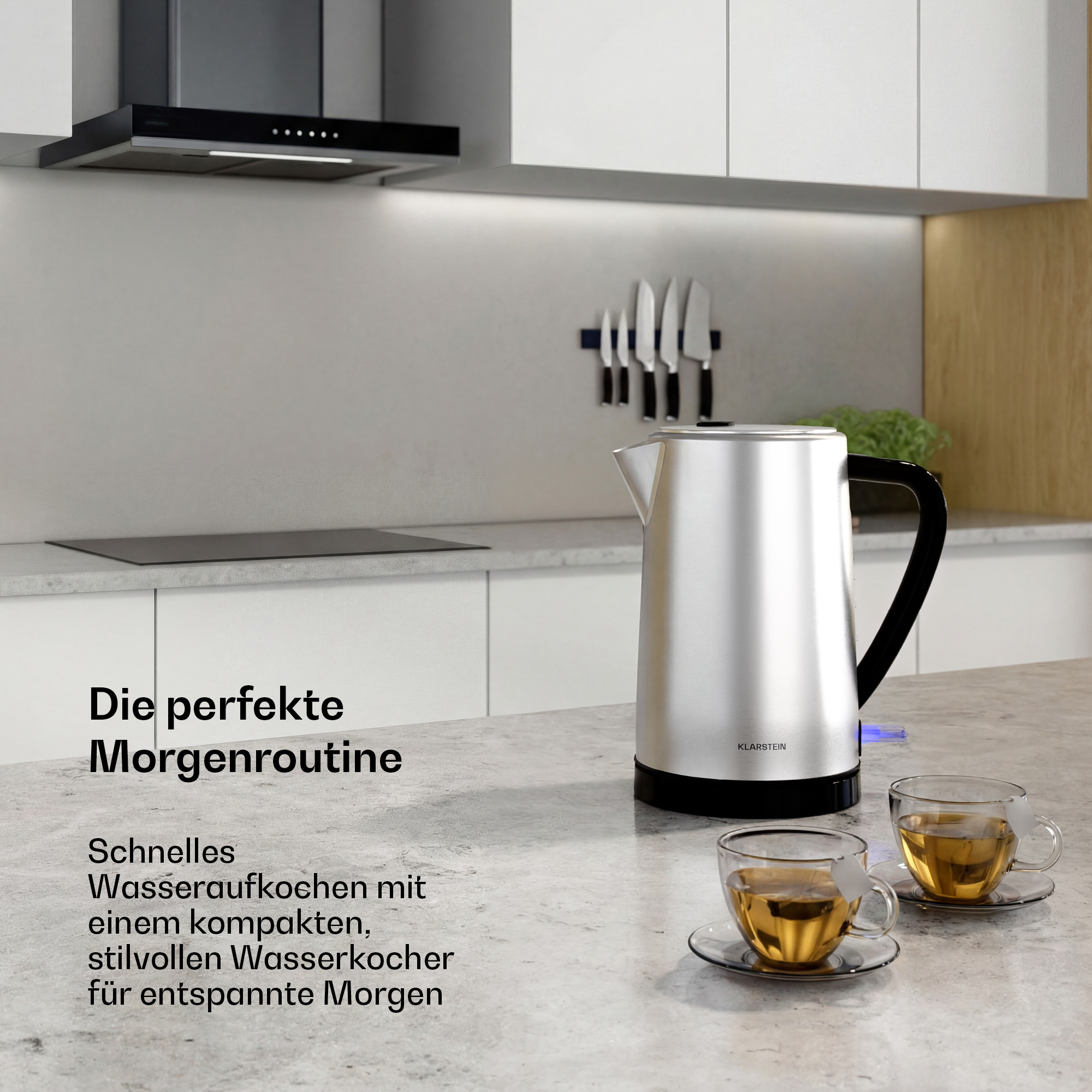 Ein silberner Wasserkocher steht auf einer Küchentheke neben zwei Tassen Tee.