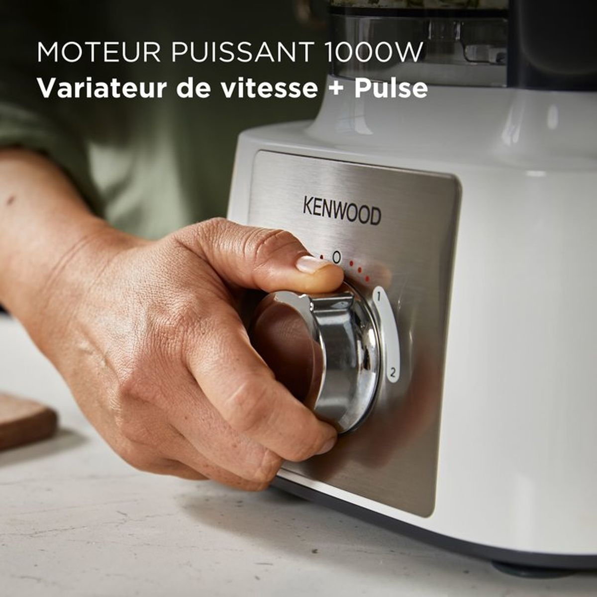 Una mano gira una manopola argentata su un Kenwood bianco.