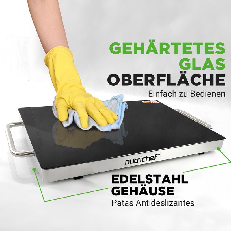 Gelbe Handschuhe wischen über schwarze Glasoberfläche eines Kochgeräts.