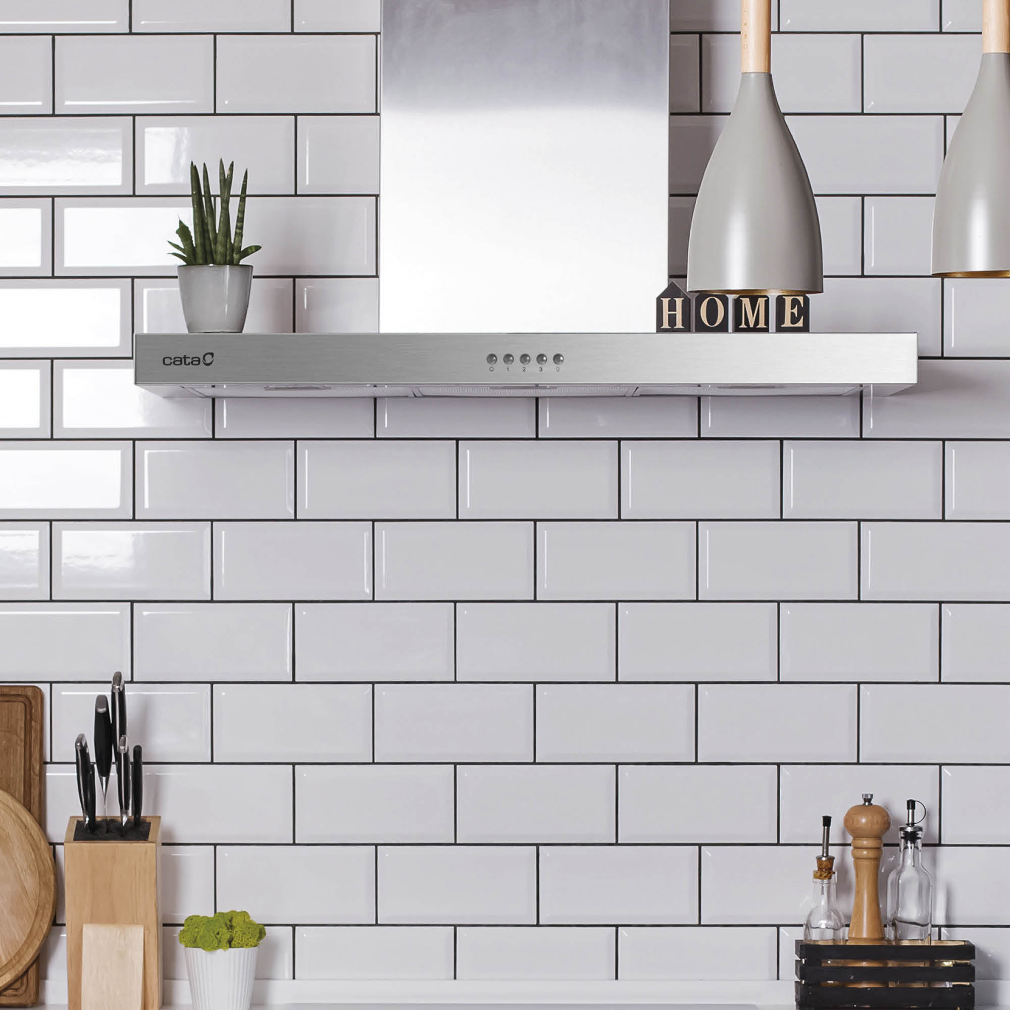 Cocina moderna con campana extractora, azulejos blancos tipo metro y decoración.