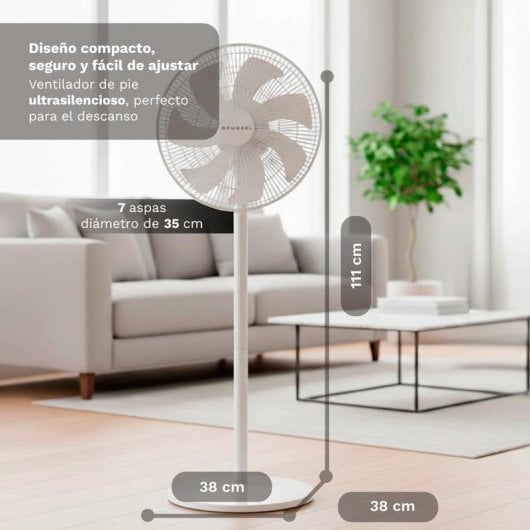Un ventilatore da terra bianco si trova in un soggiorno accanto a un divano e tavolino.