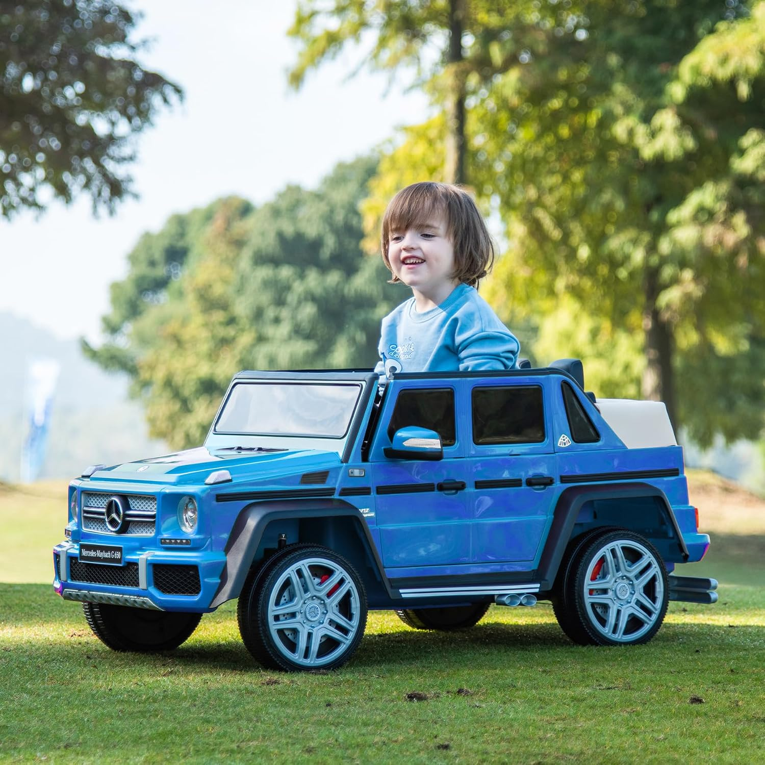Ein blaues Spielzeugauto im Freien, ein lächelndes Kind sitzt darin.
