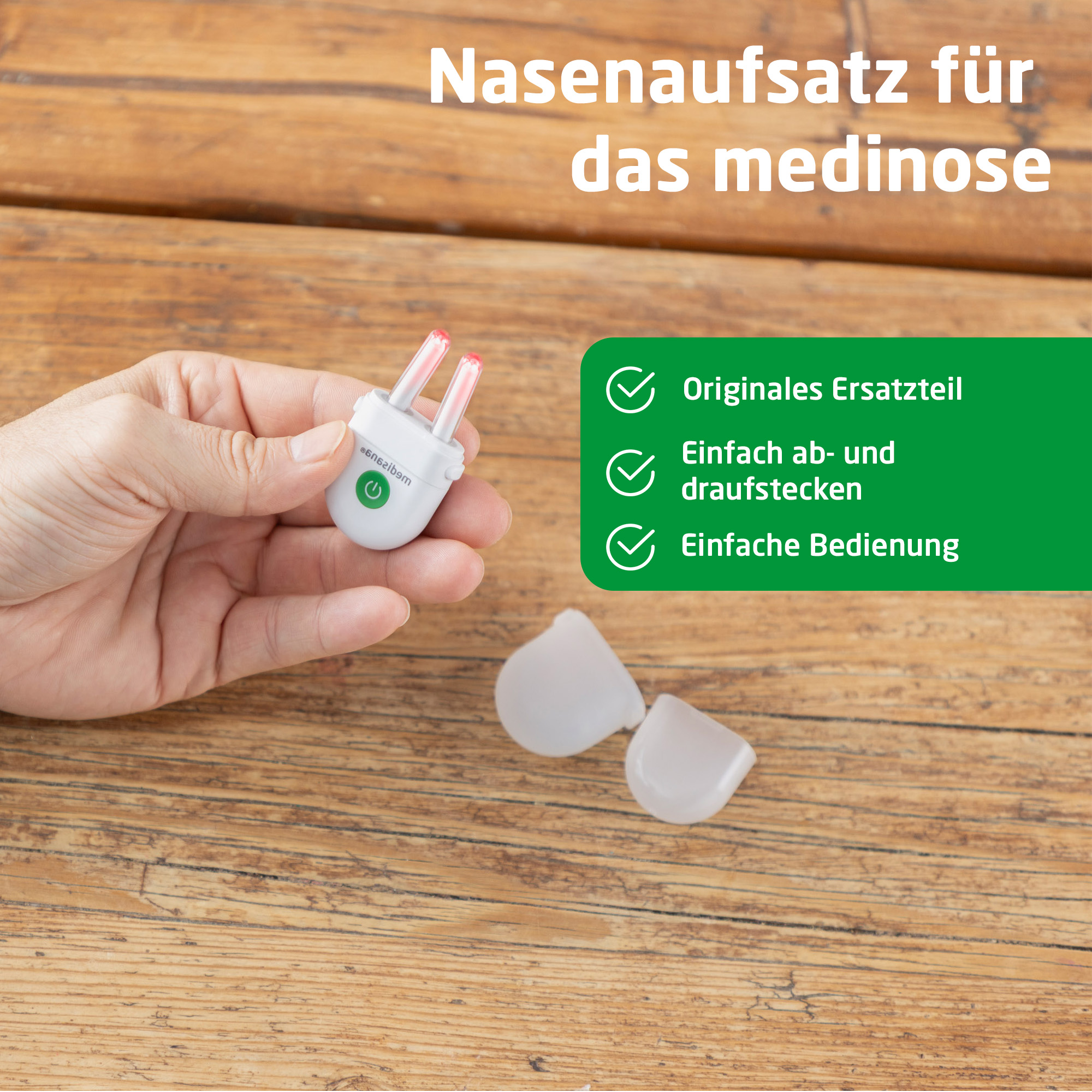 Mano sostiene accesorio nasal blanco con dos puntas rojas sobre mesa de madera.