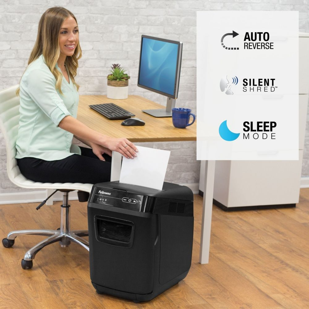 Kobieta przy biurku niszczy papier. Ikony pokazują auto reverse, silent shred, sleep mode.
