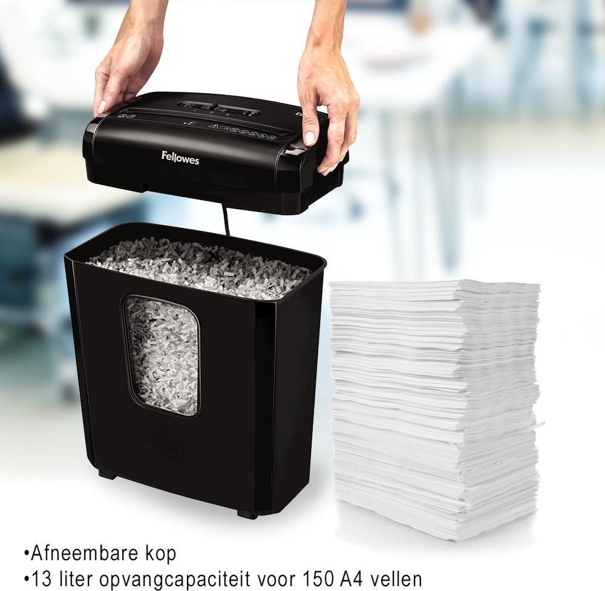 Una persona levanta una trituradora Fellowes negra de un cubo lleno de papel triturado.