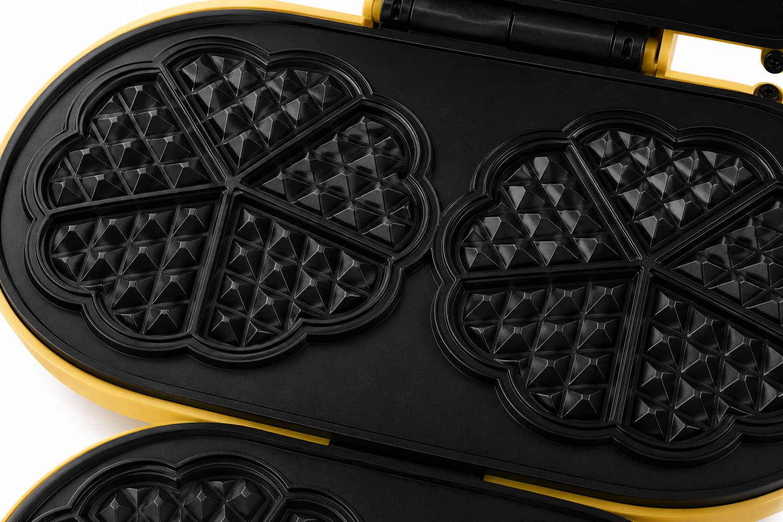 Una piastra per waffle gialla con piastre riscaldanti nere a forma di cuore.