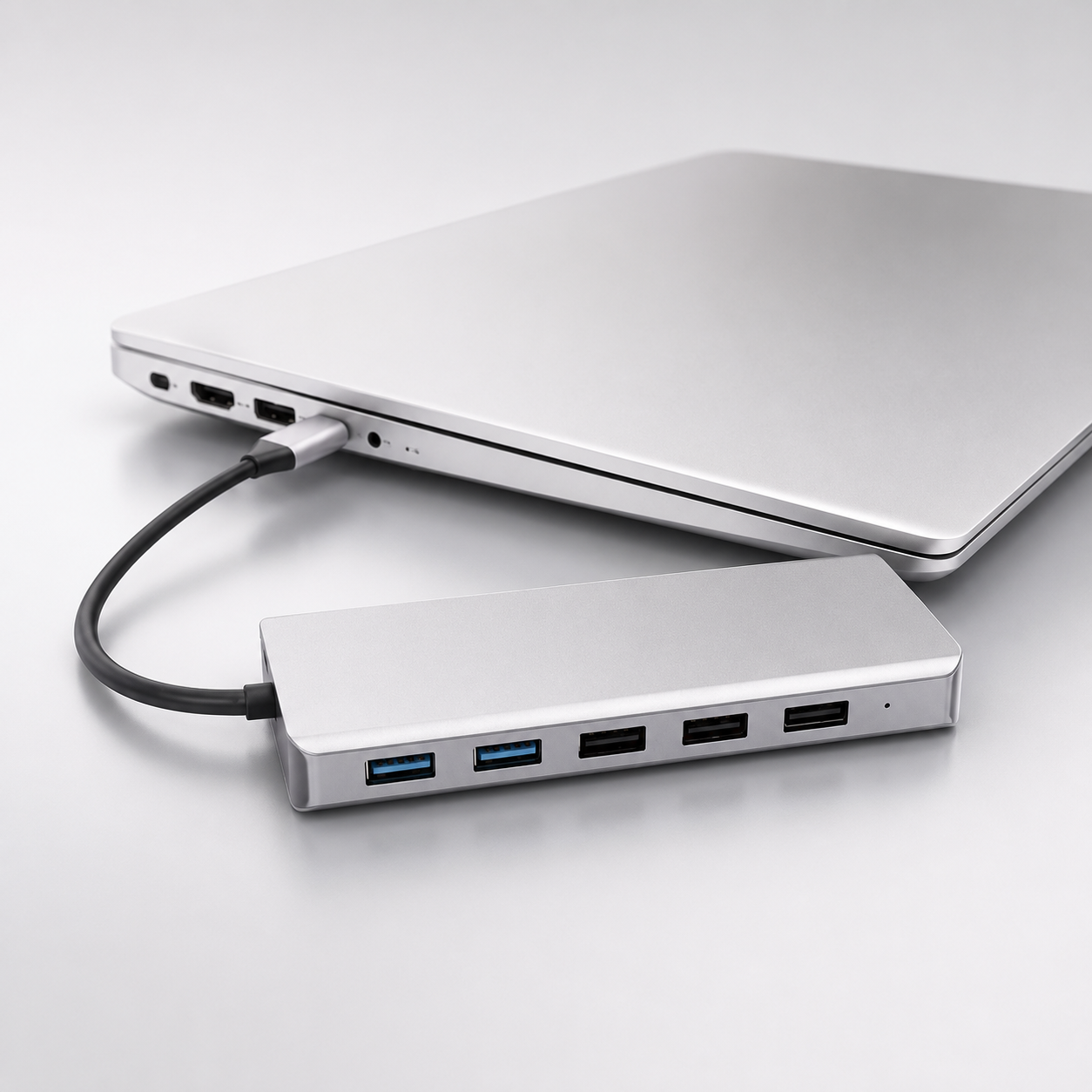 Un concentrador USB-C plateado está conectado a un portátil plateado.