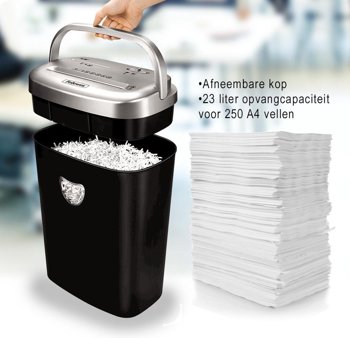 Srebrna głowica niszczarki jest podnoszona nad czarnym pojemnikiem z pociętym papierem. Stos papieru w pobliżu.
