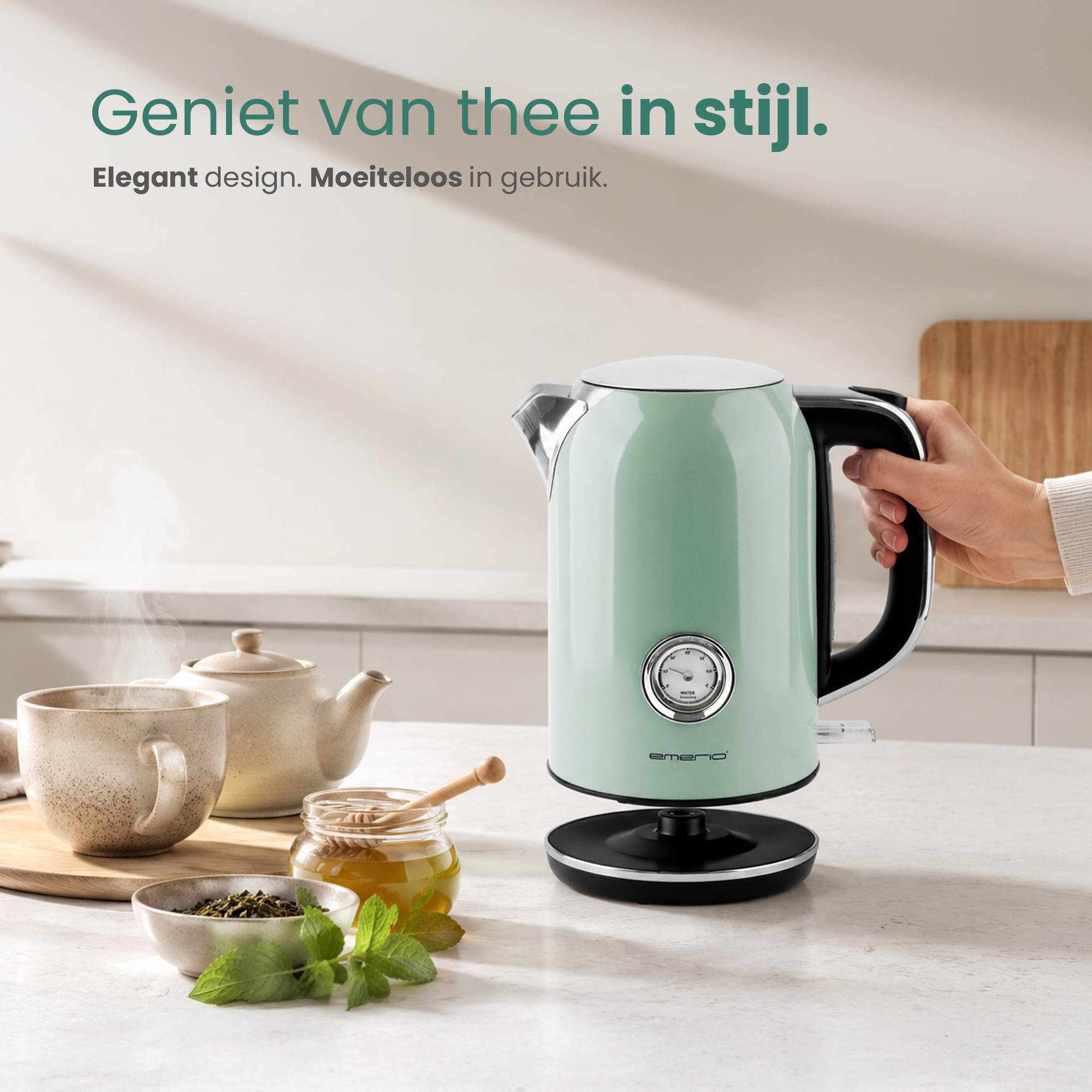 A mint green kettle sits by a cup and honey. A hand holds the handle.