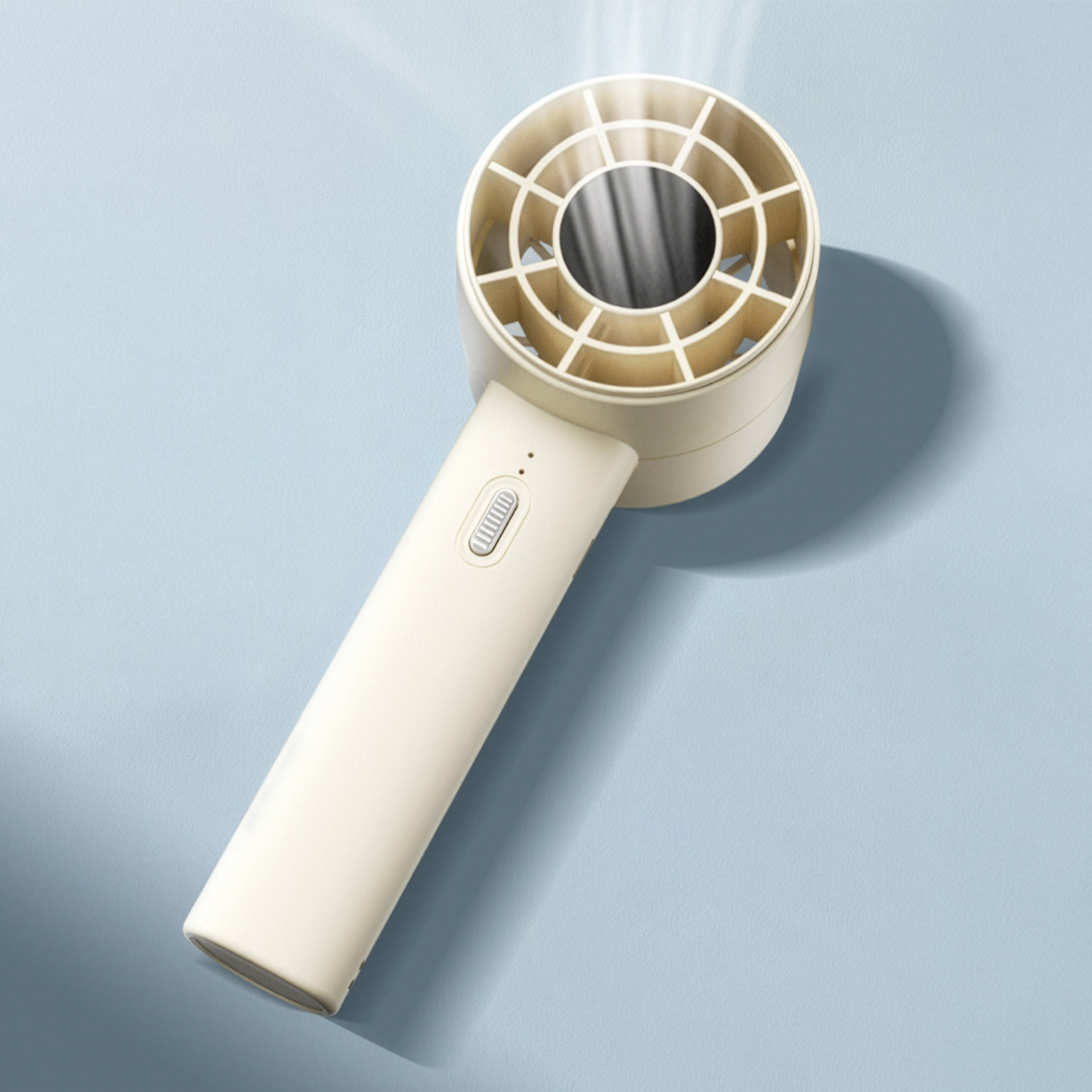 Un ventilador blanco de mano con mango beige emite una suave corriente de aire sobre superficie azul.