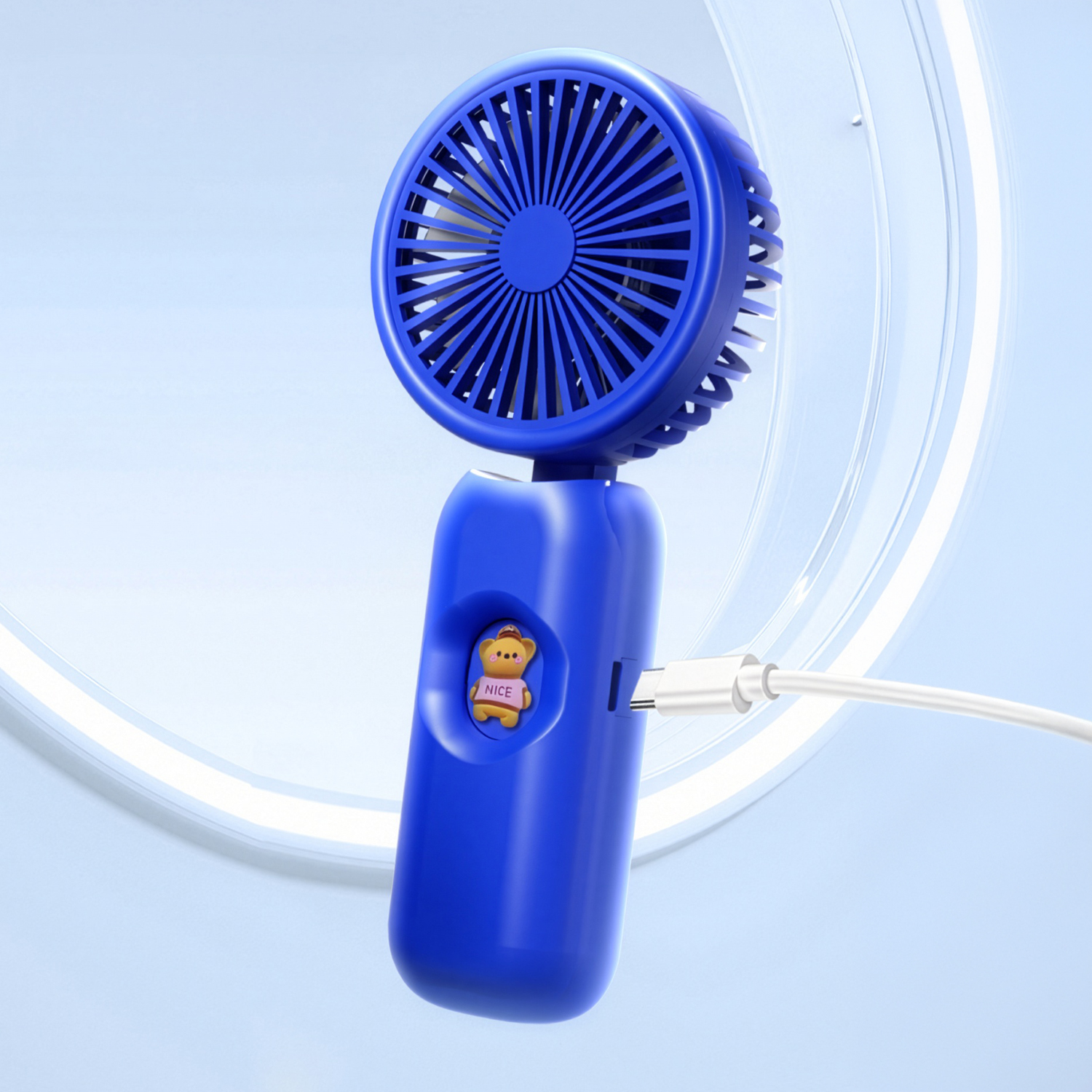 Un ventilador azul de mano con pegatina de oso de peluche y puerto USB-C.