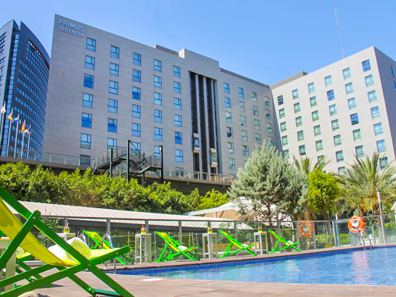 Un hotel con piscina y tumbonas delante del edificio.