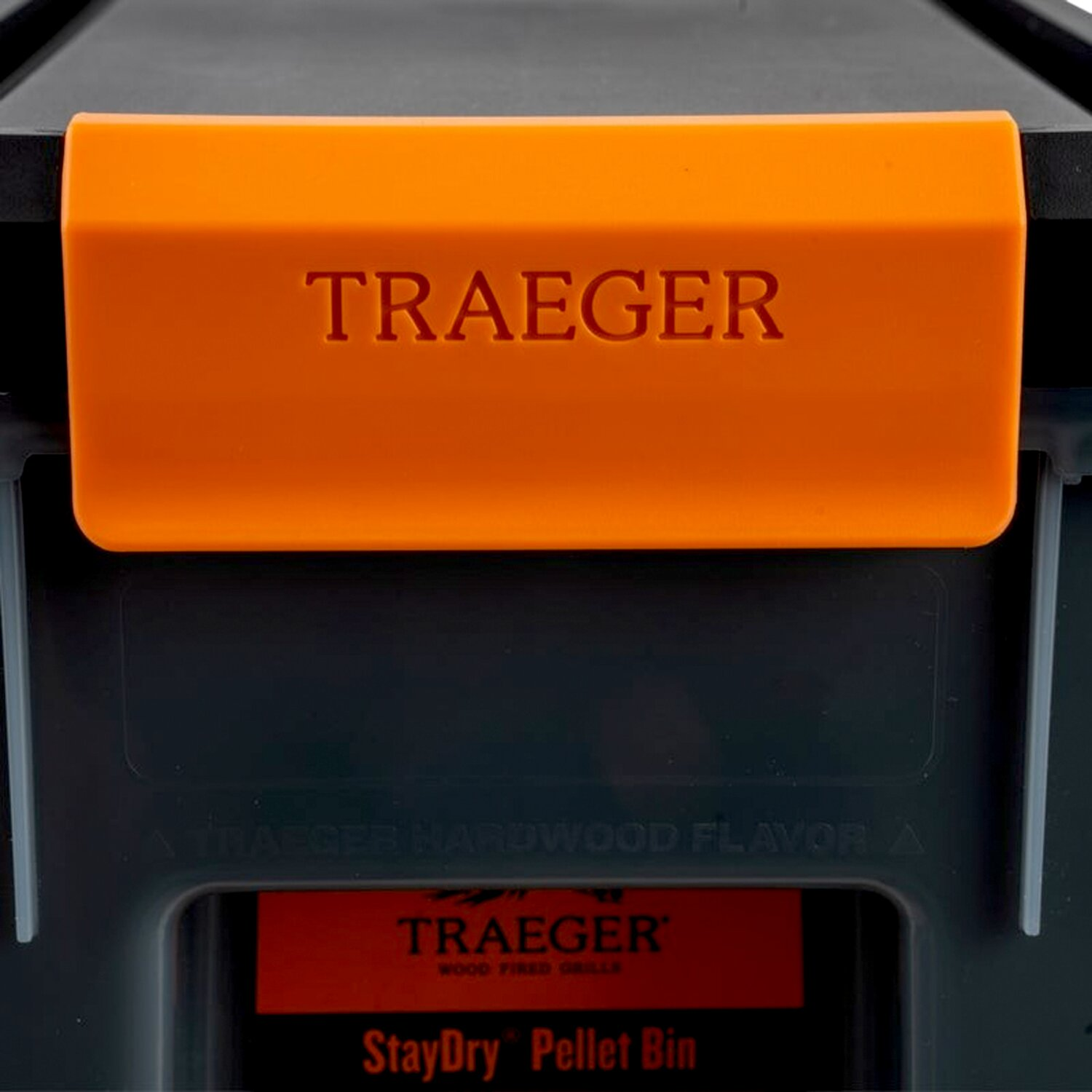 Un contenedor de pellets Traeger negro con tapa naranja y el logo Traeger.