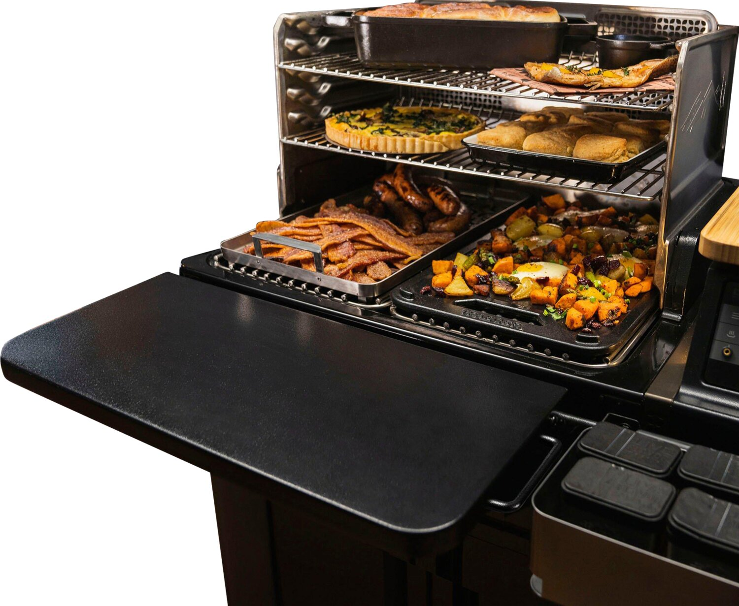 Una parrilla de varios niveles cargada con alimentos como tocino, salchichas y verduras.