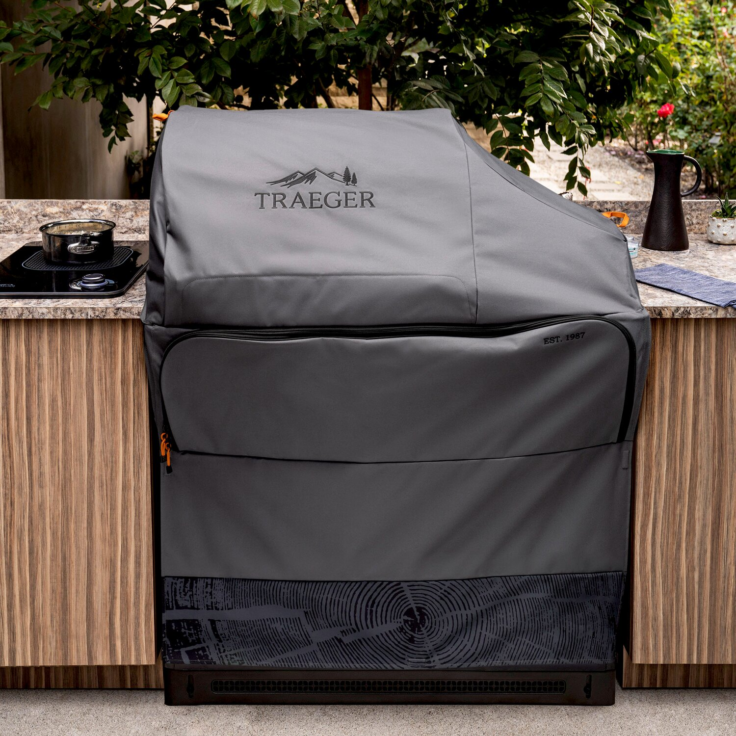 Cubierta de parrilla gris con logo Traeger en exterior, cerca de encimera.