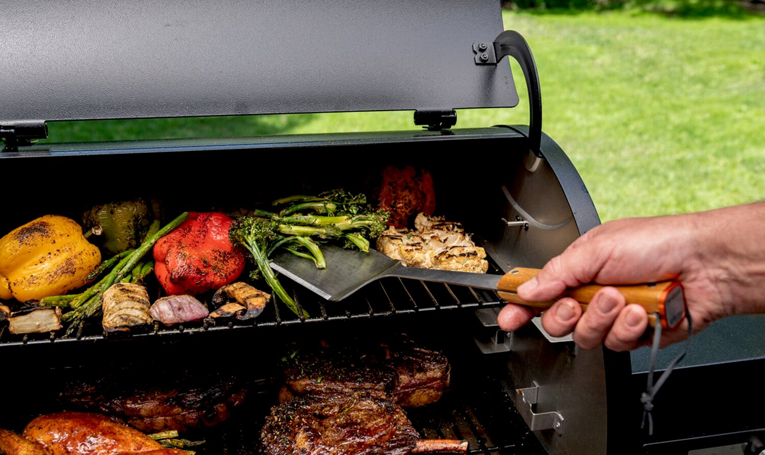 Carne y verduras se cocinan en una parrilla, volteadas a mano con espátula.