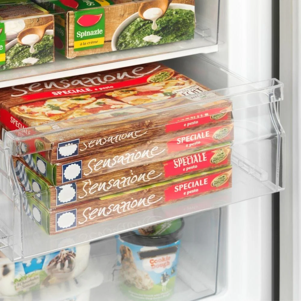 Frozen pizzas and spinach in a refrigerator.
